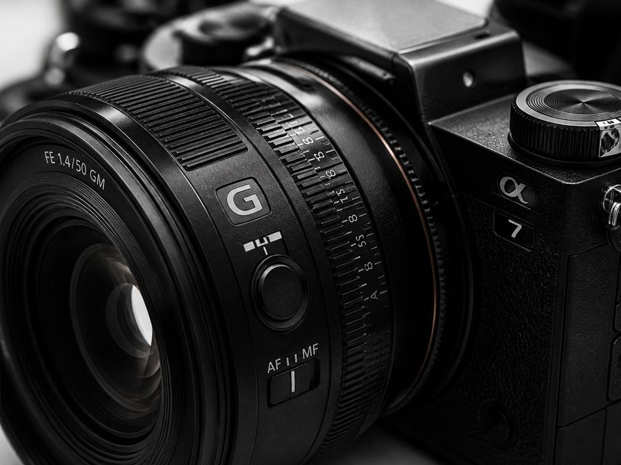 Black mirrorless camera lens, top-down on white marble